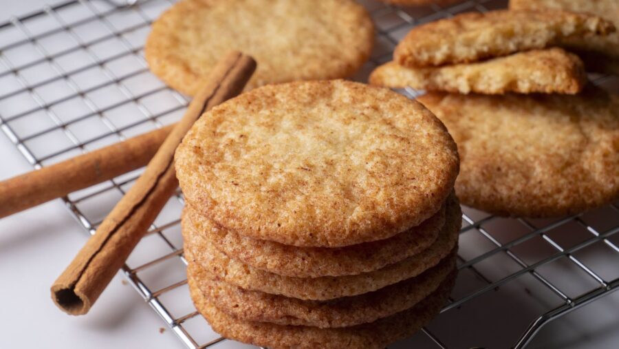 Snickerdoodle cookies on a cooling rack with cinnamon sticks.