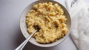 Creamy cheesy rice served in a white bowl with a spoon.