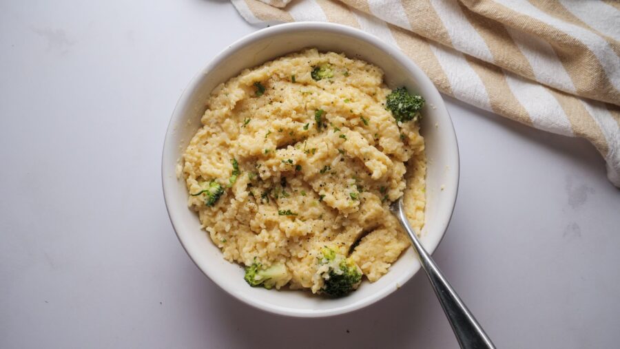 Creamy rice with broccoli and cheese in a bowl with a spoon.