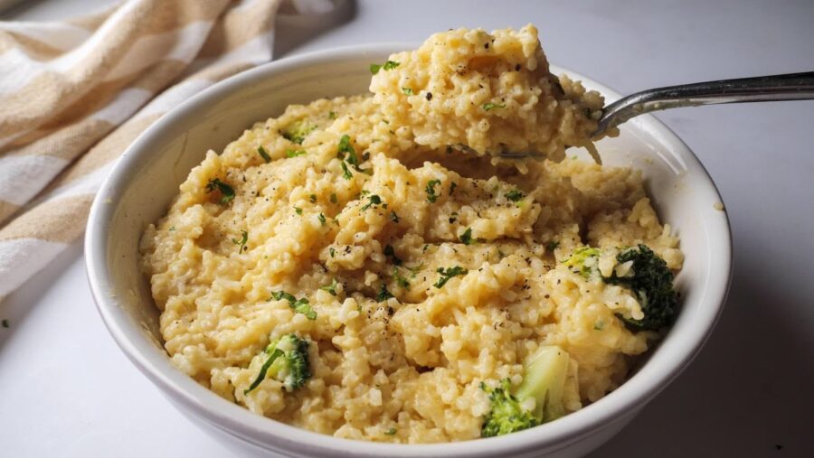 Creamy broccoli and cheesy rice in a bowl with a spoonful.