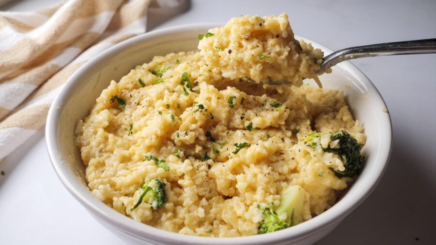 Creamy broccoli and cheesy rice in a bowl with a spoonful.