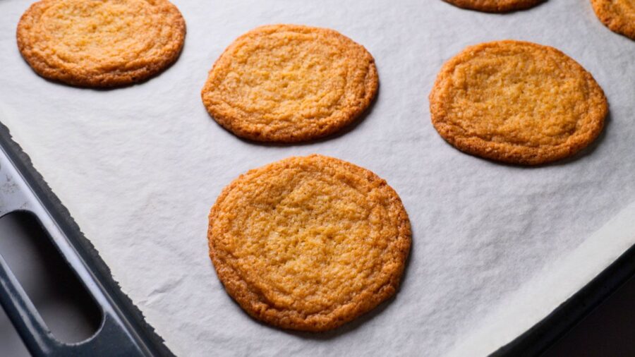 Freshly baked cookies without chocolate chips on a baking tray.