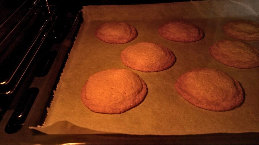 Fresh homemade cookies are baking on a sheet in the oven.