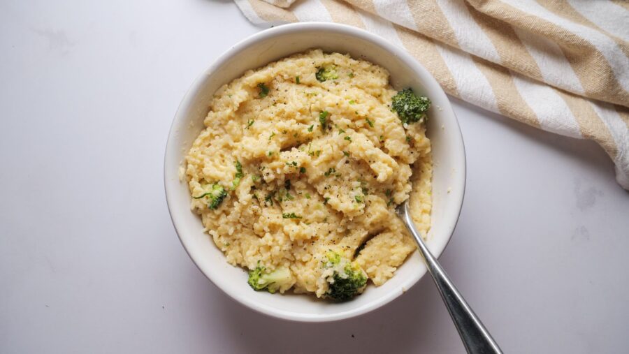 Creamy rice with broccoli and cheese in a bowl with a spoon.