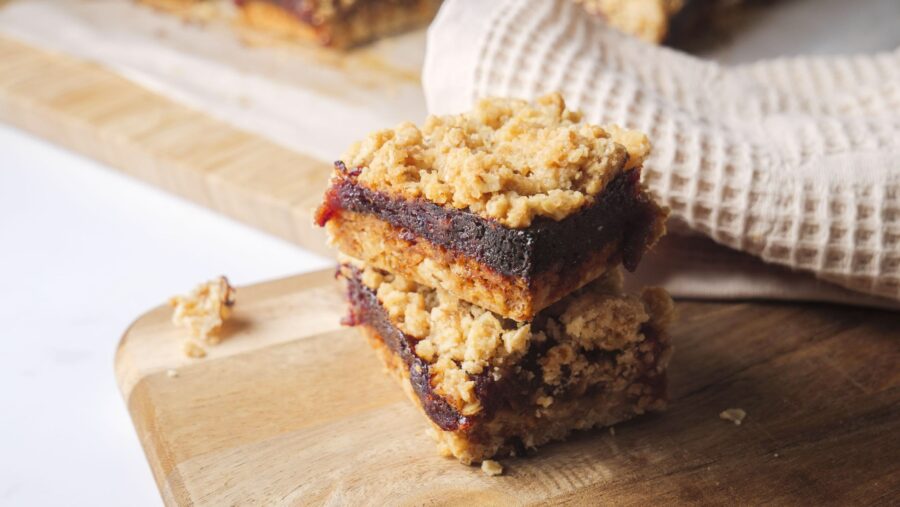Oatmeal crumble date bars stacked on a wooden board.