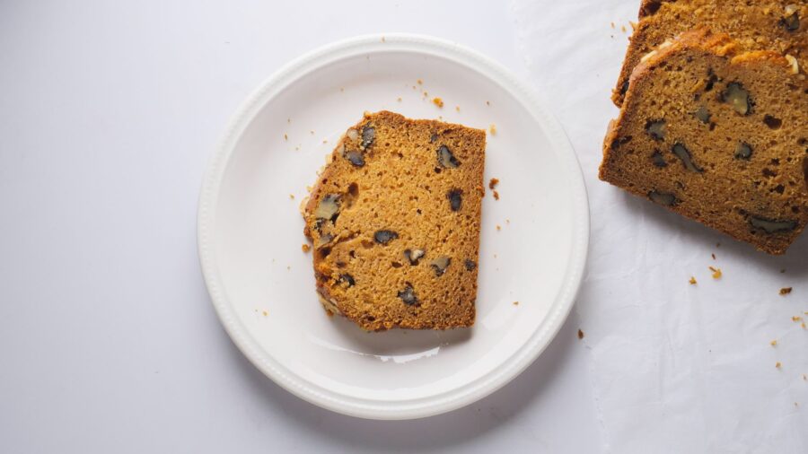 Sweet potato bread with walnut slices on a plate with more slices beside it.