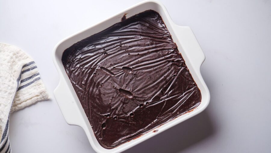 Homemade Chocolate fudge frosting in a white baking dish on a kitchen counter.