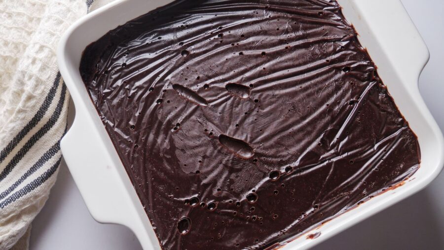 Rich chocolate fudge frosting in a white baking dish.