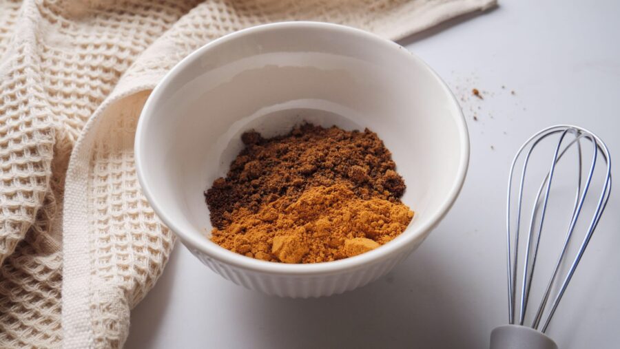 Bowl of easy substitute of Allspices with a whisk on a kitchen cloth background.