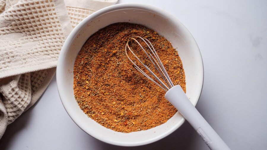 Bowl of Homemade Jamaican Jerk Seasoning with a whisk on a kitchen towel.