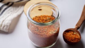 Jar of vibrant Taco Seasoning spice blend with wooden spoon.