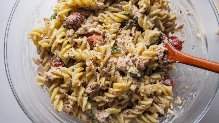Creamy tuna pasta salad with veggies in a glass bowl.