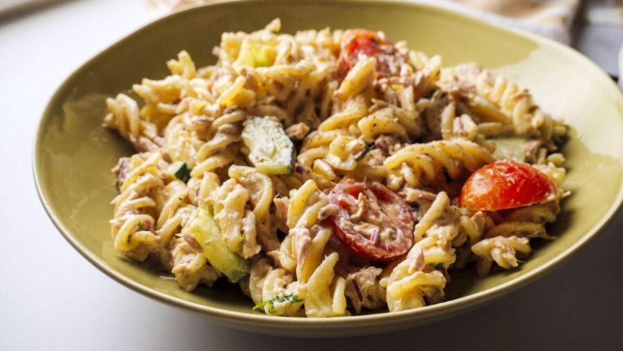 Easy Tuna pasta salad with tomatoes, cucumber, and onions in a green bowl.