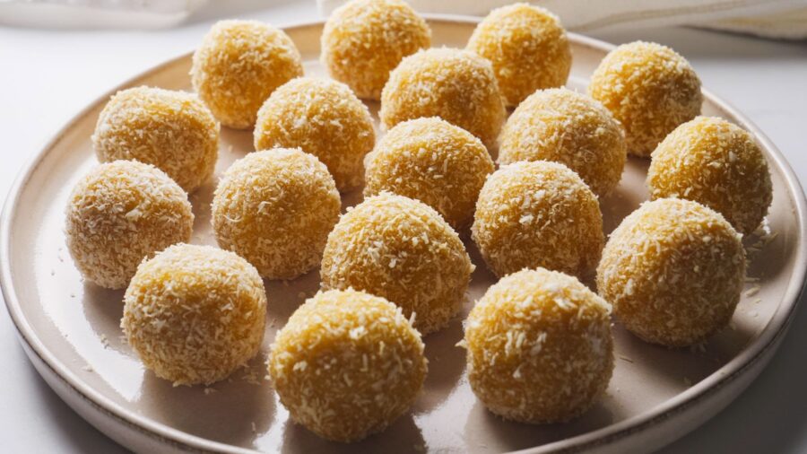 Coconut covered round no bake mango desserts truffles on a white plate