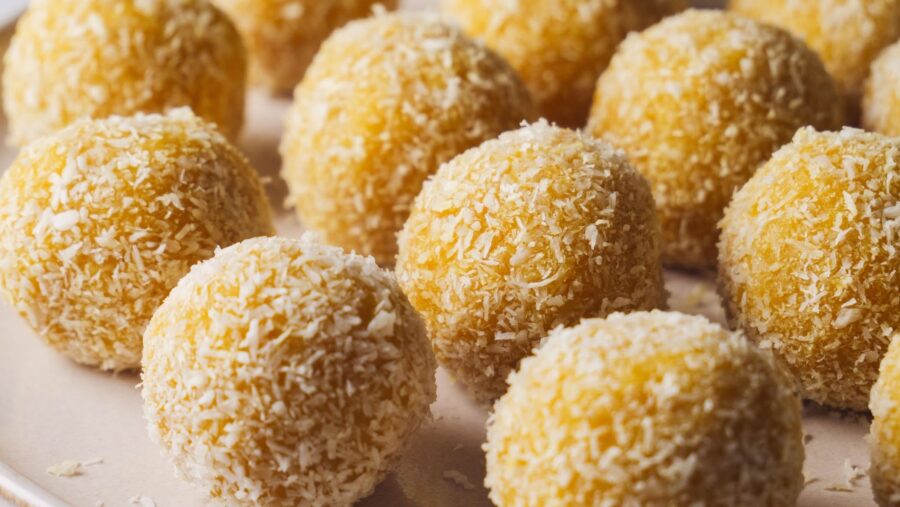 Coconut-covered no bake mango truffles on a plate.