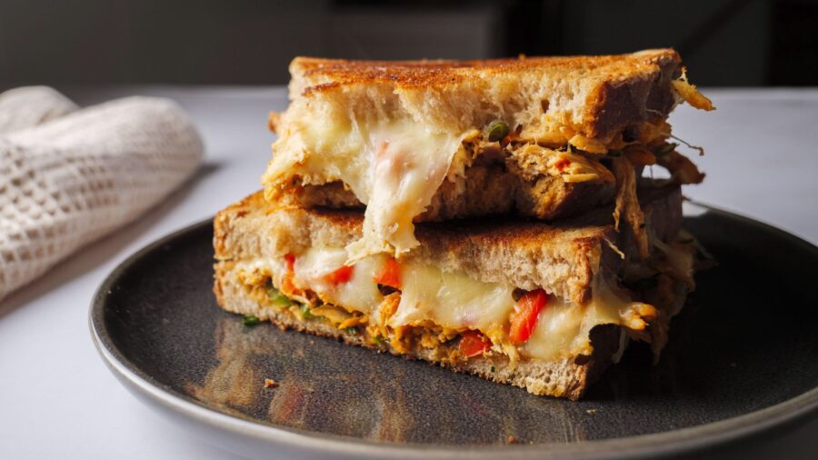 homemade chicken cheese sandwich with veggies on plate.