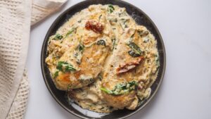 Creamy Tuscan chicken with spinach on a black plate.