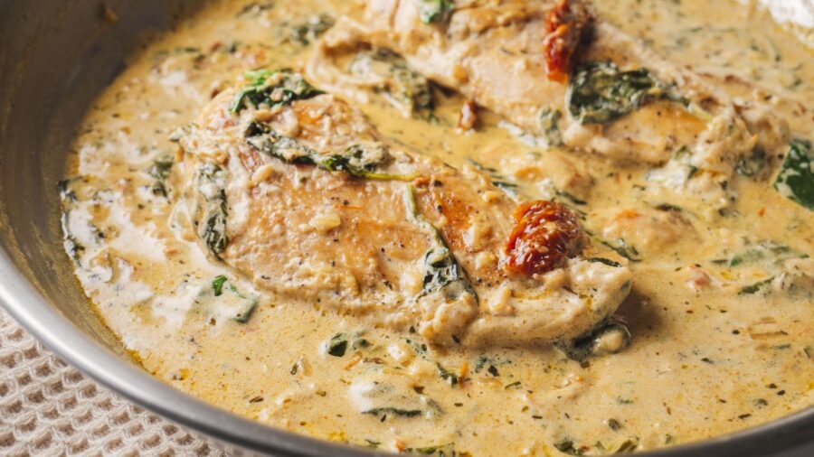 Creamy Tuscan chicken in a skillet with spinach and sundried tomatoes.