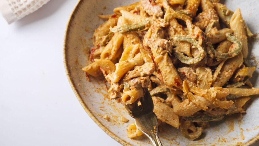 Creamy Caribbean-style pasta dish with colorful vegetable ingredients.