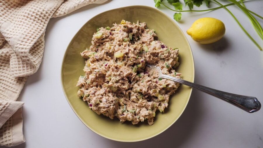 Tuna salad in a bowl with lemon and cilantro garnish.
