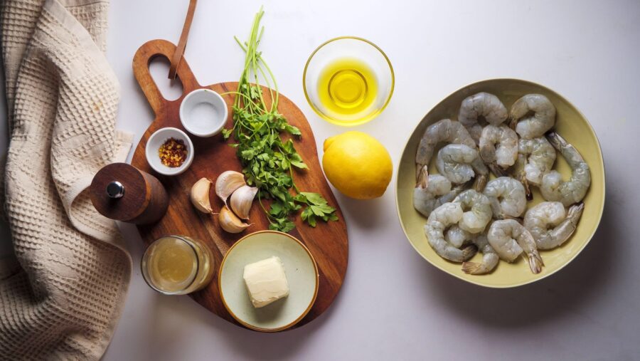 Ingredients for shrimp scampi prepared on a wooden board.