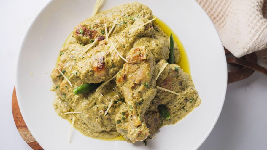 Creamy Afghan chicken with herbs and spices on a white plate.