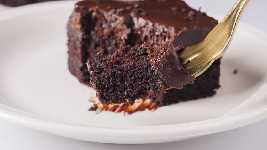 Rich chocolate sheet cake slice on plate with fork.