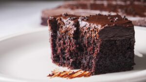 Rich chocolate sheet cake sliced on a plate.