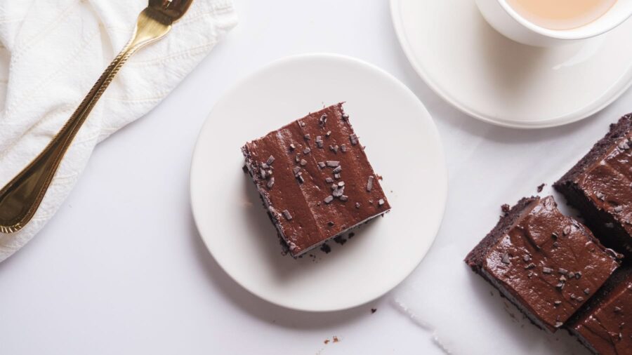 Delicious chocolate sheet cake with chocolate fudge frosting on a white plate.