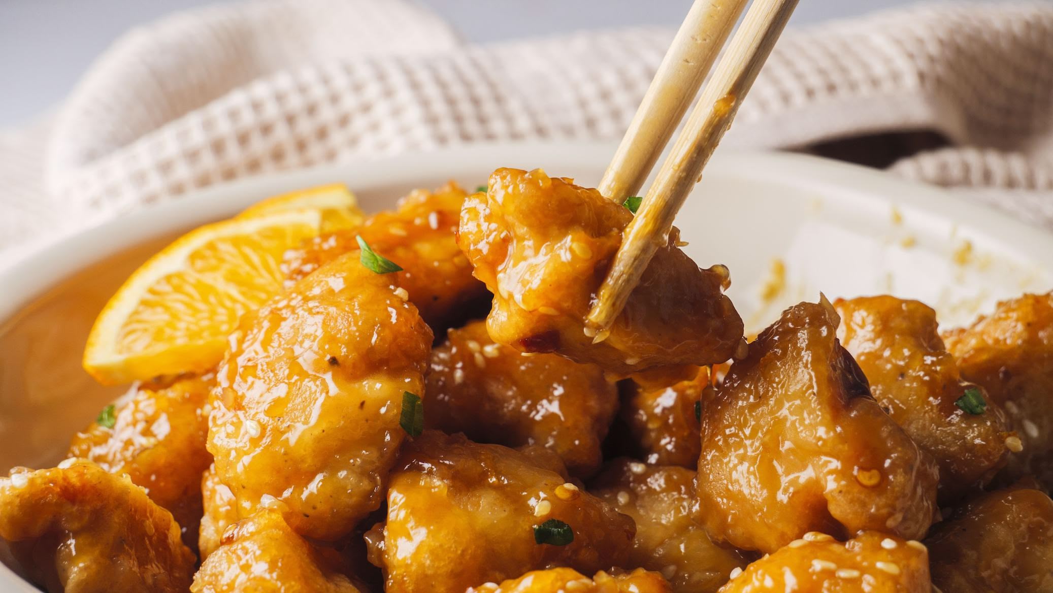 Orange chicken served with chopsticks and garnish.