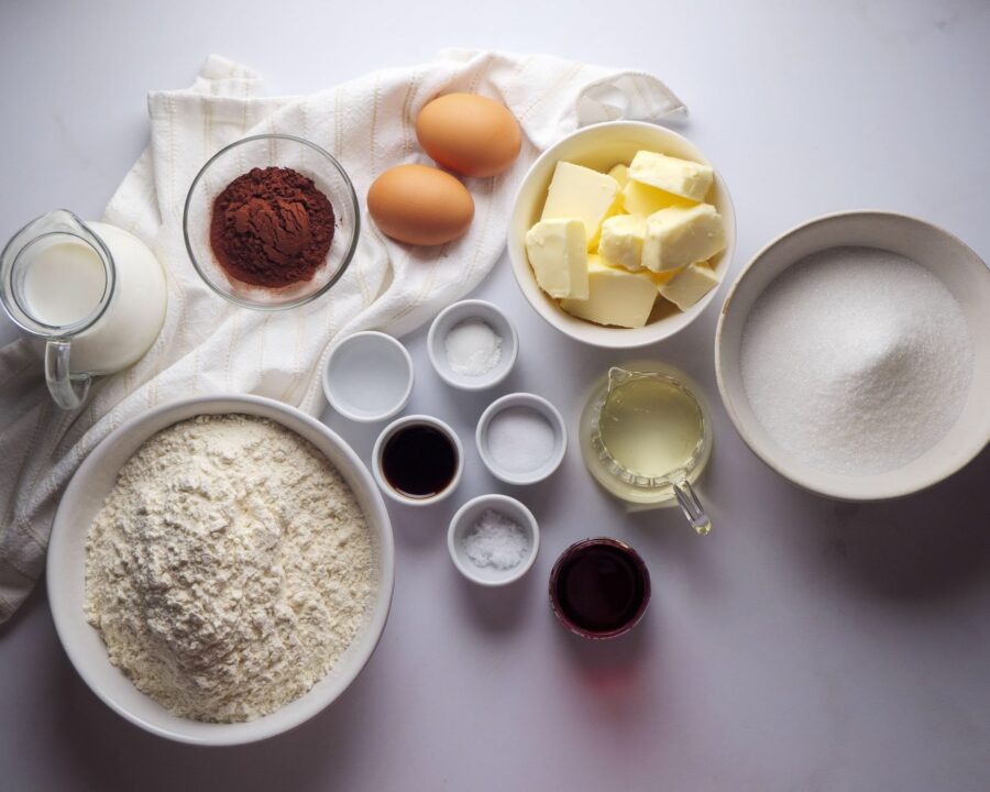 Red velvet cake baking ingredients on the table: flour, eggs, butter, sugar, and more.