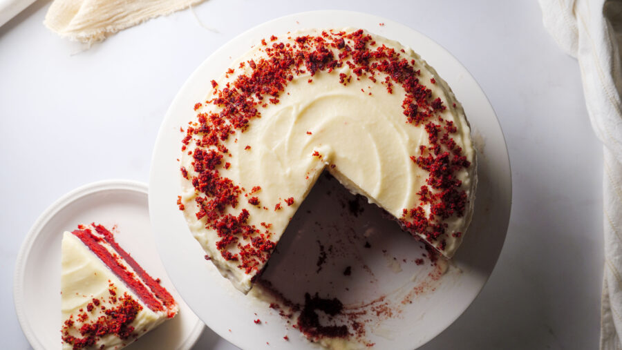 Red velvet cake with cream cheese frosting, slice removed.