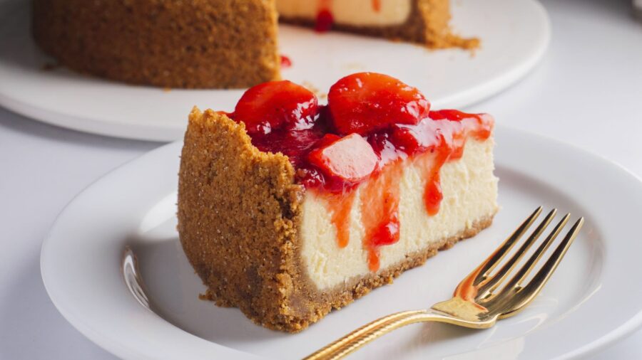 Strawberry cheesecake slice on white plate.