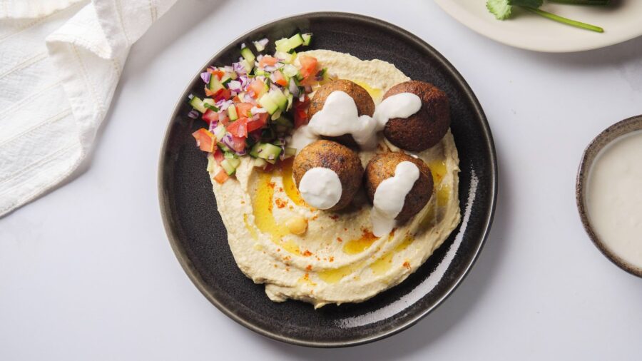 Falafel on hummus with fresh salad and yogurt drizzle.