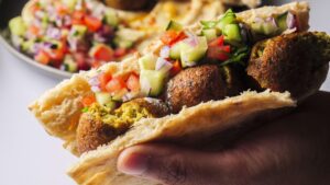 Hand holding a falafel pita with fresh veggies