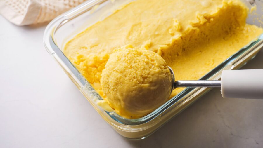 Mango Ice Cream in a box with a scoop