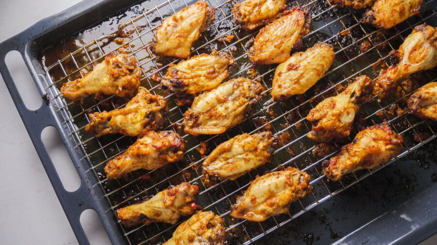 Spicy baked chicken wings on a wire rack in the oven.
