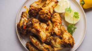 Spicy chicken wings with lemon slices on a plate.