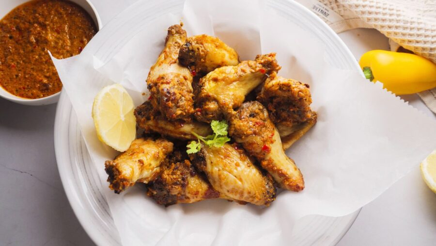 Spicy chicken wings with lemon and dip on a white plate