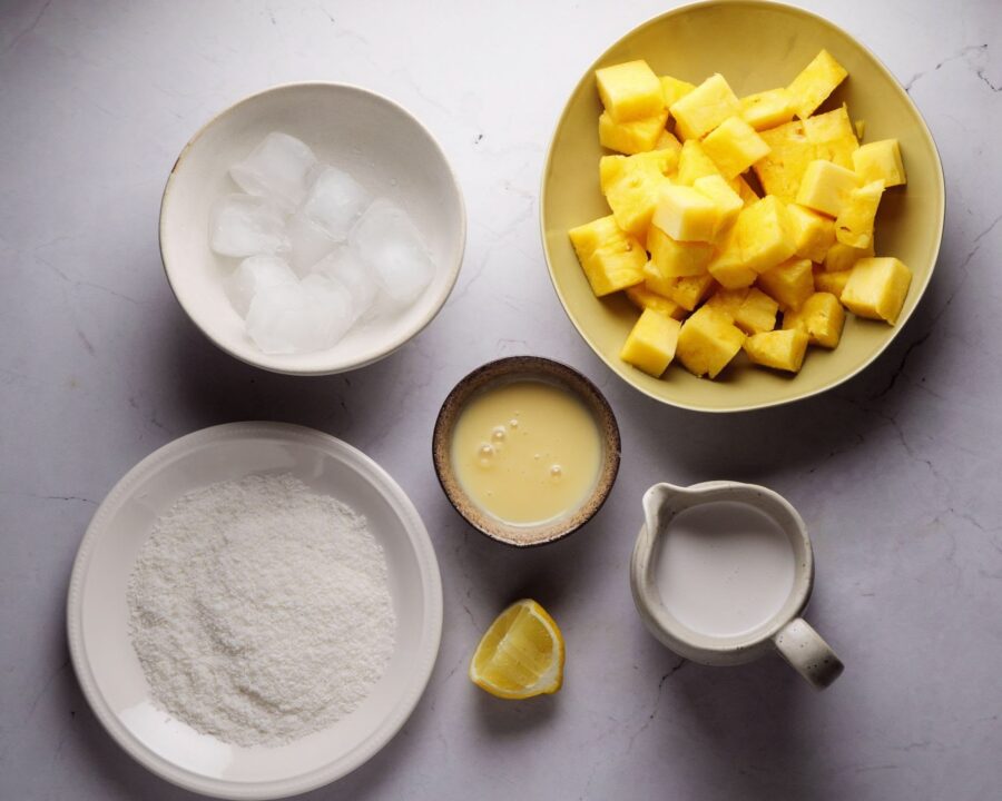 Pineapple, coconut, and ice ingredients for a tropical drink.