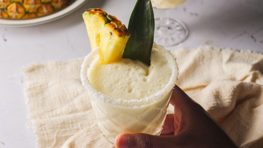 Creamy pina colada in glass with pineapple garnish.