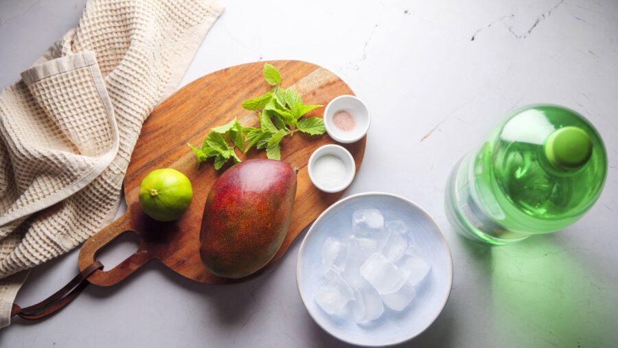 Mango, lime, and mint mocktail ingredients on a board