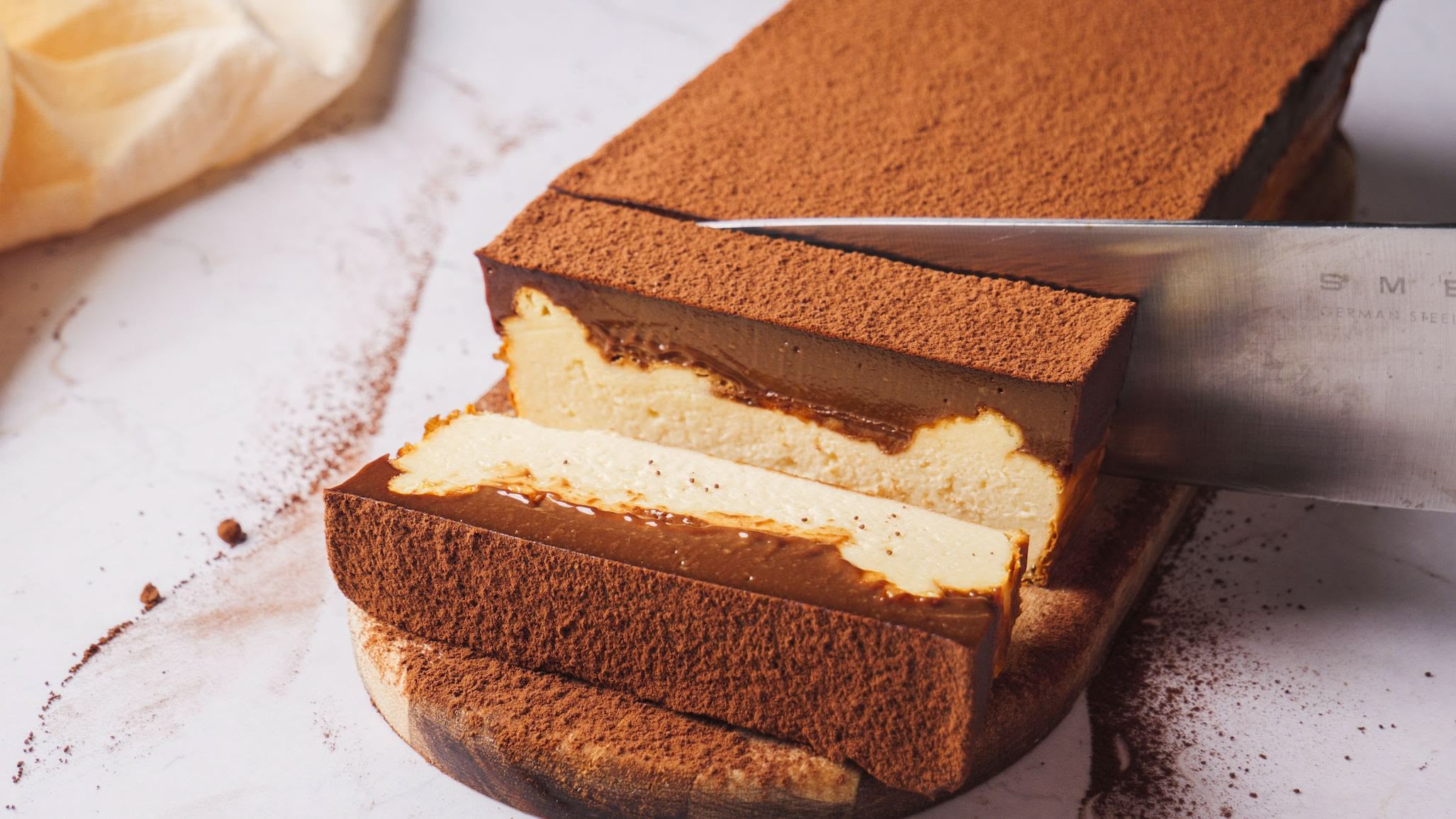 Iceberg Basque Cheesecake slice on a white board and cutting with a knife